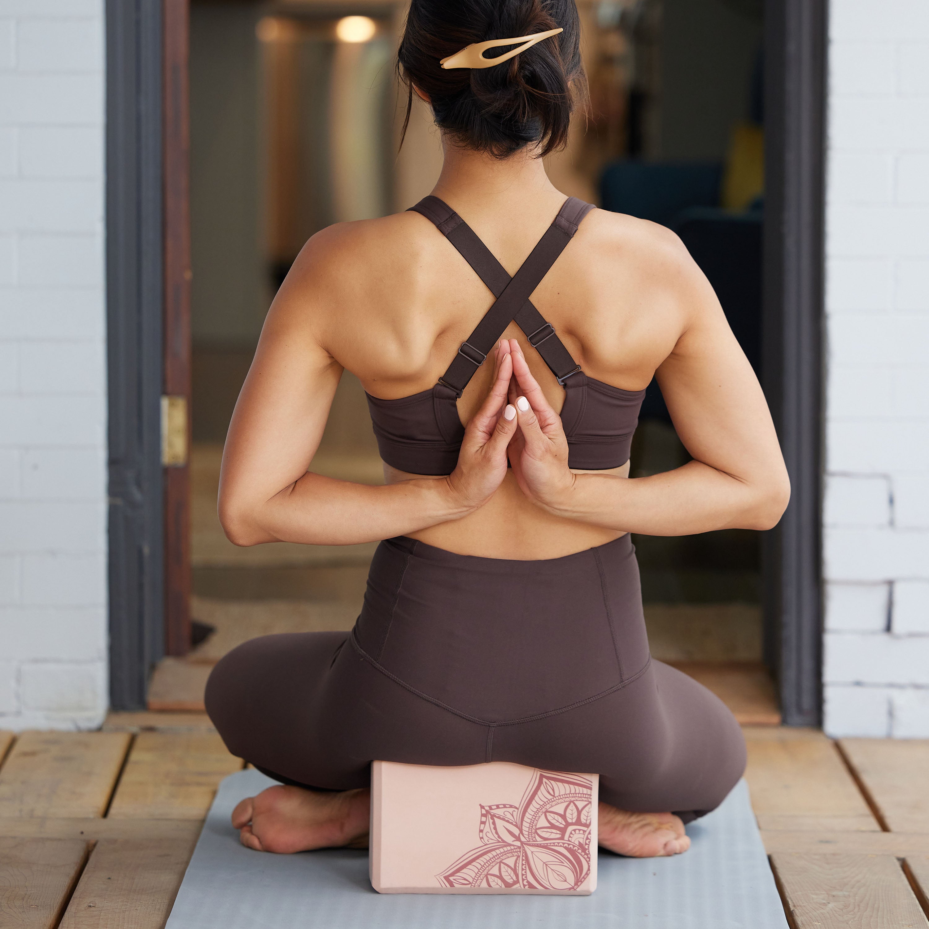 Person heated on block with back facing and hands behind back in prayer pose